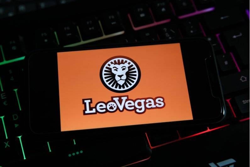 LeoVegas splash screen on a smartphone resting on a laptop keyboard