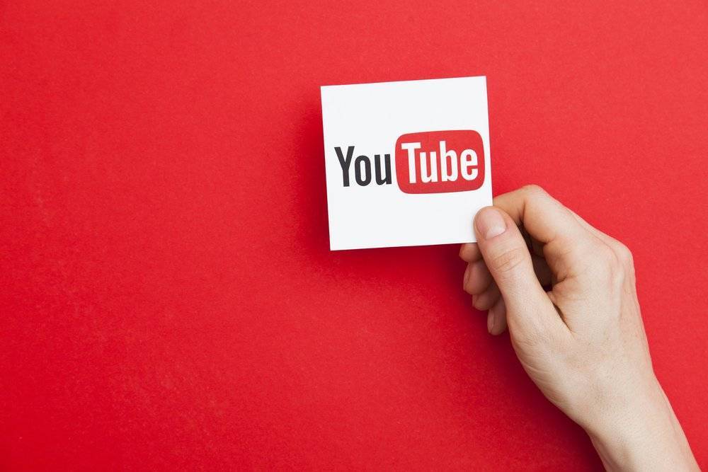 hand holding YouTube logo against red background